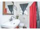 Well-lit bathroom with a single sink vanity, a window, and a shower featuring red and black curtains at 2671 Houston St, North Charleston, SC 29405