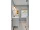 This bathroom features a marble countertop, white vanity, oval mirror, a window, and a partial glass shower enclosure at 2802 Ion Ave, Sullivans Island, SC 29482