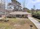 Charming single-story brick home with a well-manicured lawn, mature trees, and a cozy front porch with rocking chairs at 303 Gippy Dr, Summerville, SC 29486