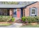 Close-up of a brick home's inviting pink front door framed by lush landscaping at 313 Runnymede Ln, Summerville, SC 29485