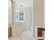 Bright bathroom featuring marble floors, vanity with vessel sink, and tub with glass shower door at 32 Prioleau St # N, Charleston, SC 29401