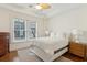 Cozy bedroom with large window, ceiling fan, hardwood floors, and white bedding and two side tables at 32 Prioleau St # N, Charleston, SC 29401
