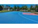 Outdoor basketball court with blue and red surfaces, surrounded by fencing and lush greenery at 425 Verbena Ave, Summerville, SC 29483