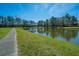 Lush green lawn and sidewalk leading to a pond with trees and blue skies in the background at 425 Verbena Ave, Summerville, SC 29483