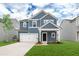 Charming two-story home features a blue exterior, well-manicured lawn, and an attached white two-car garage at 588 Red Monarch Way, Moncks Corner, SC 29461