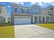 Charming two-story home featuring a gray shingle and stone exterior, a two-car garage, and a well-manicured lawn at 591 Red Monarch Way, Moncks Corner, SC 29461