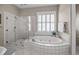 Elegant bathroom with a glass-enclosed shower and a luxurious soaking tub with tile surround at 707 Ocean Blvd, Isle of Palms, SC 29451