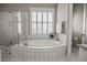 Luxurious bathroom showcasing a large soaking tub with tiled surround and plantation shutters at 707 Ocean Blvd, Isle of Palms, SC 29451