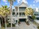 Stunning three-story beach house with multiple balconies, palm trees, and a brick driveway at 707 Ocean Blvd, Isle of Palms, SC 29451