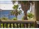 View of ocean and blue beach home through tropical foliage from an outdoor patio at 707 Ocean Blvd, Isle of Palms, SC 29451