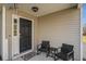 Inviting covered front porch featuring wicker seating, a small table and decorative welcome mat at 8005 Old Hazelwood Rd, North Charleston, SC 29406