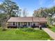 Charming brick home featuring a landscaped front yard with mature trees, shrubs, and a paved driveway at 1039 Grand Concourse St, Charleston, SC 29412