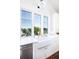 Farmhouse sink with white cabinets and stainless steel appliances with view of greenery at 1302 Middle St, Sullivans Island, SC 29482