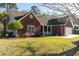 A well-maintained brick home featuring a covered porch, manicured lawn, and attached two-car garage at 1633 Wayah Dr, Charleston, SC 29414