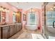 Elegant pink bathroom with a standalone tub, walk-in shower, double vanity, and ample natural light at 1874 Rifle Range Rd, Mount Pleasant, SC 29464