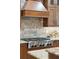 Close-up of stainless steel cooktop in kitchen with granite countertops and tile backsplash at 1874 Rifle Range Rd, Mount Pleasant, SC 29464