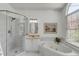 Bright bathroom with marble floors, soaking tub, walk-in shower, and large arched window at 1988 Long Creek Rd, Wadmalaw Island, SC 29487