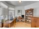 Sunlit office featuring a wooden desk, built-in shelves, and a large window with blinds at 1988 Long Creek Rd, Wadmalaw Island, SC 29487