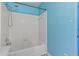 The bathroom has a tub and shower with white tiled walls and contrasting blue walls at 201 Commons Way, Goose Creek, SC 29445