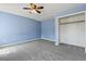 Bright blue bedroom with gray carpet, ceiling fan, and an open closet at 201 Commons Way, Goose Creek, SC 29445