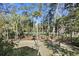 Serene backyard view with mature trees, lush lawn, and glimpses of the golf course beyond at 2440 Cat Tail Pond Rd, Seabrook Island, SC 29455