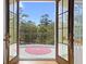 Balcony view through open French doors, showcasing an outdoor space with a pink rug and lush greenery at 2440 Cat Tail Pond Rd, Seabrook Island, SC 29455