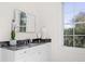 Modern vanity with dark countertops, decorative accessories, and white cabinets at 2440 Cat Tail Pond Rd, Seabrook Island, SC 29455