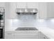 Modern kitchen with white cabinets, stainless steel range hood, cooktop, and marble countertops at 2440 Cat Tail Pond Rd, Seabrook Island, SC 29455