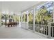 Expansive covered porch with outdoor seating, ceiling fan, and scenic views of the surrounding greenery at 2440 Cat Tail Pond Rd, Seabrook Island, SC 29455