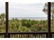 A beautiful view of the ocean from a wooden porch beyond lush green trees at 263 Pelican Flight Dr, 15.4% Share, Dewees Island, SC 29451