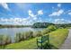 Scenic lake view with a green bench, lush trees, blue sky, and fluffy clouds at 2739 Calico Bass Ln, Johns Island, SC 29455