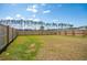 Large, grassy backyard enclosed by a wooden fence, and treeline with a pond beyond at 284 Shadybrook Dr, Summerville, SC 29486