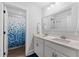 Bathroom with double vanity, bright lighting, and a tub with a blue and white curtain at 306 Long Pier St, Summerville, SC 29486