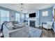 Well-lit living room featuring a gray sectional sofa, fireplace, and large windows at 3537 Sewel Ave, Mount Pleasant, SC 29466