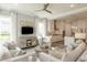 Bright living room with white couches, white curtains, ceiling fan, and open concept kitchen in the background at 4004 Flatiron Dr, Charleston, SC 29414