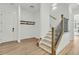A modern entryway with light wood floors, white walls, a staircase with dark metal railings, and coat hooks at 4036 Azalea Farms Way, McClellanville, SC 29458