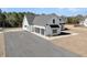 A modern farmhouse-style home features a white exterior, black trim, a gravel driveway, and an attached two-car garage at 4036 Azalea Farms Way, McClellanville, SC 29458