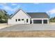 Side view of home featuring three-car garage, gravel driveway and low windows at 4036 Azalea Farms Way, McClellanville, SC 29458