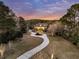 Aerial view of a charming home with a long, winding driveway surrounded by lush landscaping and trees at dusk at 4051 Colonel Vanderhorst Cir, Mount Pleasant, SC 29466