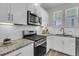 Contemporary kitchen boasts stainless steel appliances, granite countertops, and sleek white cabinetry at 565 Blueway Ave, Summerville, SC 29486