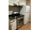 Close-up view of kitchen with stainless steel appliances, white cabinets, and black countertops at 6601 Dorchester Rd # 109, North Charleston, SC 29418