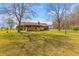 Expansive backyard features a charming house with a cozy porch, mature trees, and open grass at 729 2Nd Bend Rd, Harleyville, SC 29448