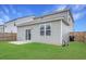 View of a well-maintained backyard with green grass, patio, and a light gray house against a blue sky at 131 Horizon Ridge Dr, Summerville, SC 29486