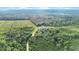 An aerial view showcases a lush landscape, complete with a tranquil pond and a house surrounded by dense trees at 13959 Cottageville Hwy, Cottageville, SC 29435