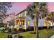 A side view of a two-story home, highlighting its well-lit windows, green lawn, and surrounding palm trees against a pink sky at 1525 Harriman St, Mount Pleasant, SC 29466