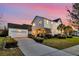 View of the home's back exterior, featuring a detached garage, a paved driveway, and a well-kept lawn at dusk at 1525 Harriman St, Mount Pleasant, SC 29466