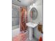 Bright bathroom with patterned rug, white pedestal sink, and shower with colorful shower curtain at 171 Broad St, Charleston, SC 29401