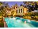 Inviting pool area with elegant lighting, patio furniture, and a view of the charming yellow house at twilight at 171 Broad St, Charleston, SC 29401