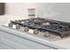 This kitchen features a high end cooktop on white quartz countertops and minimalist, gray cabinetry at 2135 Tides End Rd, Charleston, SC 29412