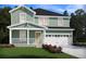 Charming two-story home showcasing a light green facade, covered front porch, and attached two-car garage at 321 Calm Water Way, Summerville, SC 29486